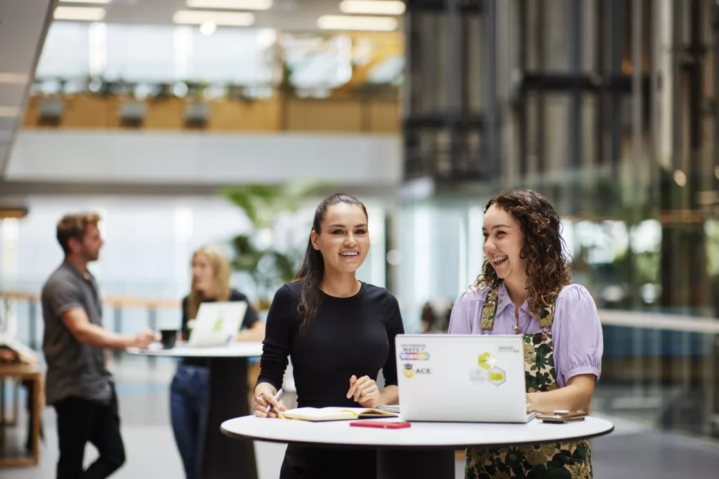 A photo of two people working on a laptop.