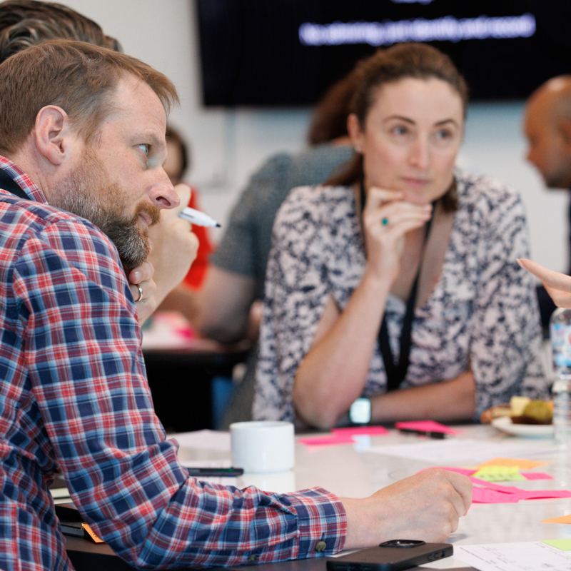 A photo of people sitting at a table and talking to each other.