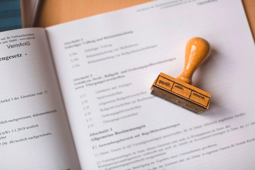 A photo of a wooden stamp lying on top of a document about regulation.
