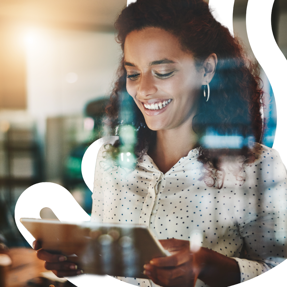 A photo of a woman standing in an official, smiling down at a digital tablet.