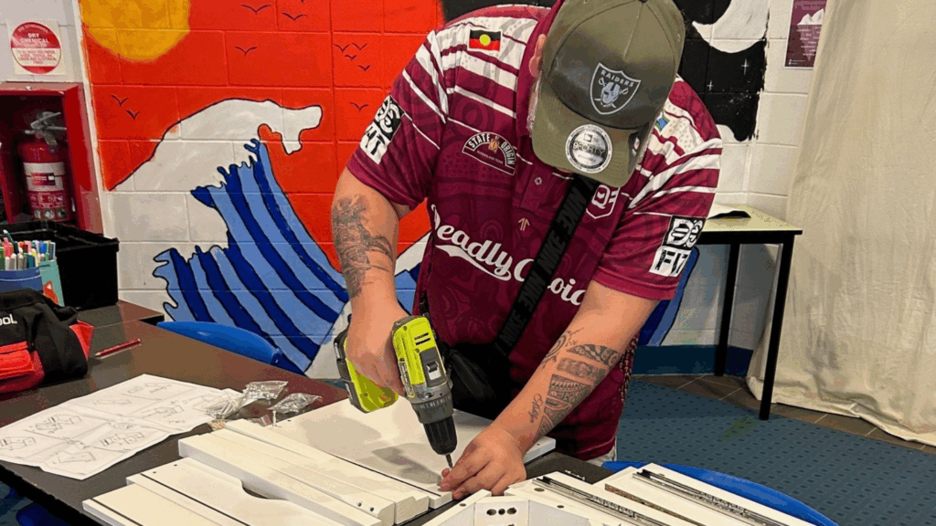 A photo of a man building furniture.