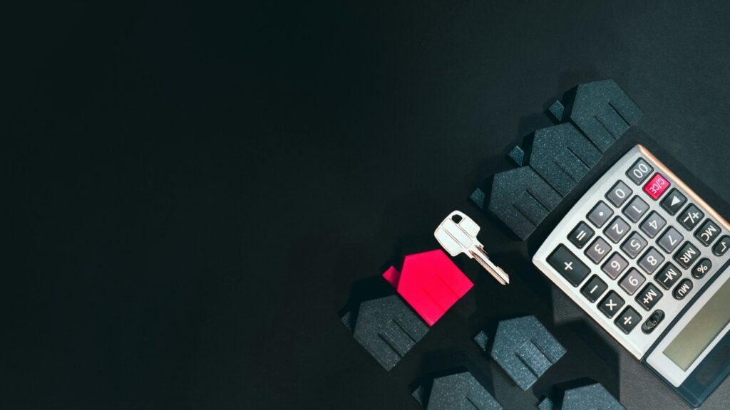 A photo of a key and a calculator on a desk.